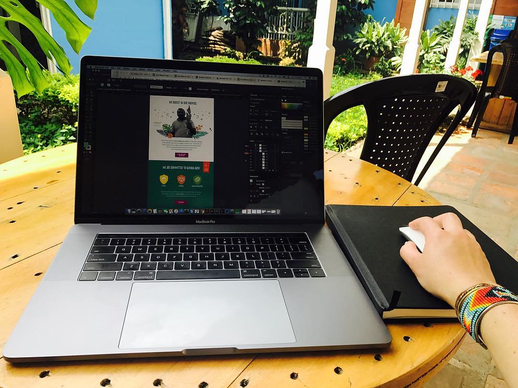 person using macbook pro on white table